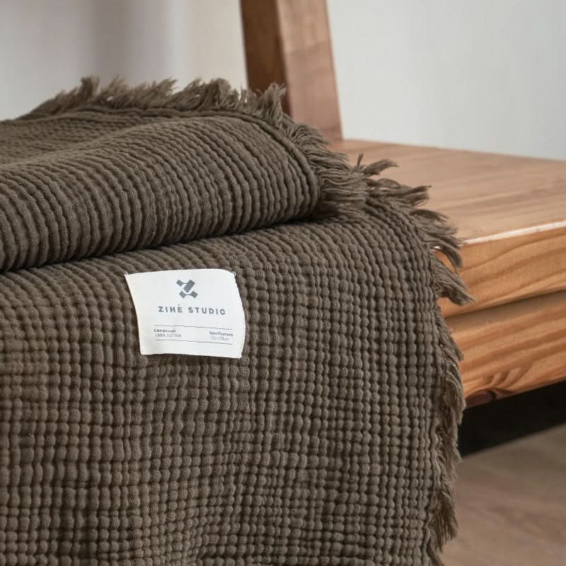 Cozy Textured Cotton Throw Blanket in taupe with fringe detail on wooden surface.